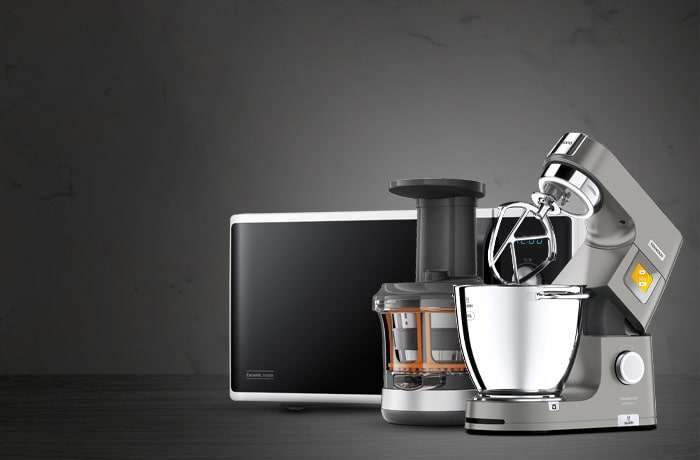 Modern kitchen appliances including a microwave, juicer, and stand mixer on a sleek countertop against a dark gray, marbled background.